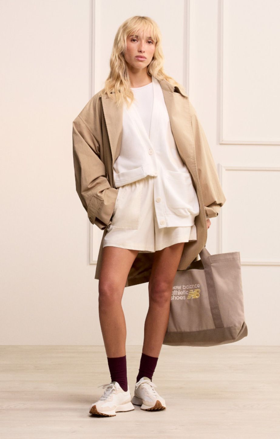 woman standing holding a new balance bag and wearing new balance 327 sneakers